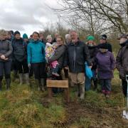 Elaine Rigg's family gathered around the plaque naming Elaine's Wood
