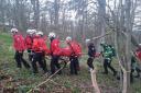 Rescue services team up to help patient in a medical emergency next to a river bank.