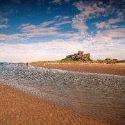 SERENE: Bamburgh Castle and beach as two people walk towards the castle