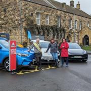 Zaria Greenhill, Cllr Suzanne Fairless-Aiken, and Cllr Ariane Baty stood next to some of the electric vehicles on show